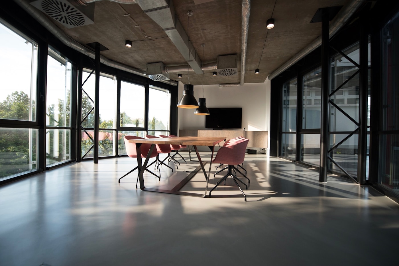 Sunlit creative studio with a long wooden table and modern chairs